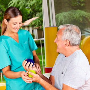 photograph of man being assisted with wrist exercises by therapist