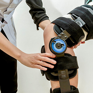 Woman with knee brace assisted by physiotherapist
