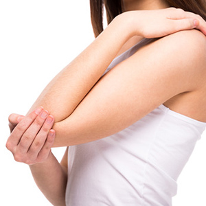Photograph of woman in pain holding her elbow.